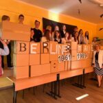 uczniowie z kartonami przedstawiającymi mur berliński