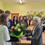 uczniowie wręczają kwiaty