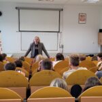 sala wykładowa, prowadzący, uczniowie siedzący w ławkach