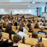 uczniowie siedzący na sali wykładowej słuchający prelekcji