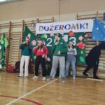 napis "dożeromki", uczniowie biorący udział w szkolnym wydarzeniu na sali gimnastycznej
