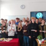 uczniowie pozujący do zdjęcia, trzymają tradycyjne potrawy hiszpańskie