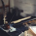 biurko z kałamarzem, piórek i stertą dokumentów