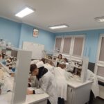 uczniowie w fartuchach podczas zajęć laboratoryjnych z chemii w szkolnym laboratorium