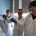 uczniowie w odzieży ochronnej podczas zajęć w laboratorium chemicznym