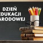 stos książek, okulary i kredki w pojemniku, obok napis "dzień edukacji narodowej"