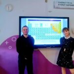 uczniowie stojący przy monitorze multimedialnym