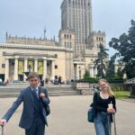 uczniowie stojący na tle pałacu kultury