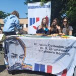 uczniowie siedzący przy stoisku szkoły