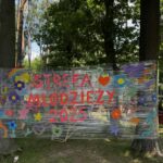 napis rozwieszony na drzewach