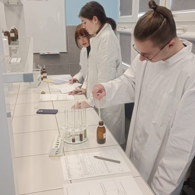 uczniowie w fartuchach podczas zajęć laboratoryjnych z chemii w szkolnym laboratorium